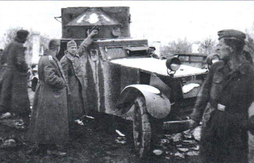 1940 г. Немецкие солдаты рассматривают захваченный броневик White времен Первой мировой войны с деревянными спицованными колёсами