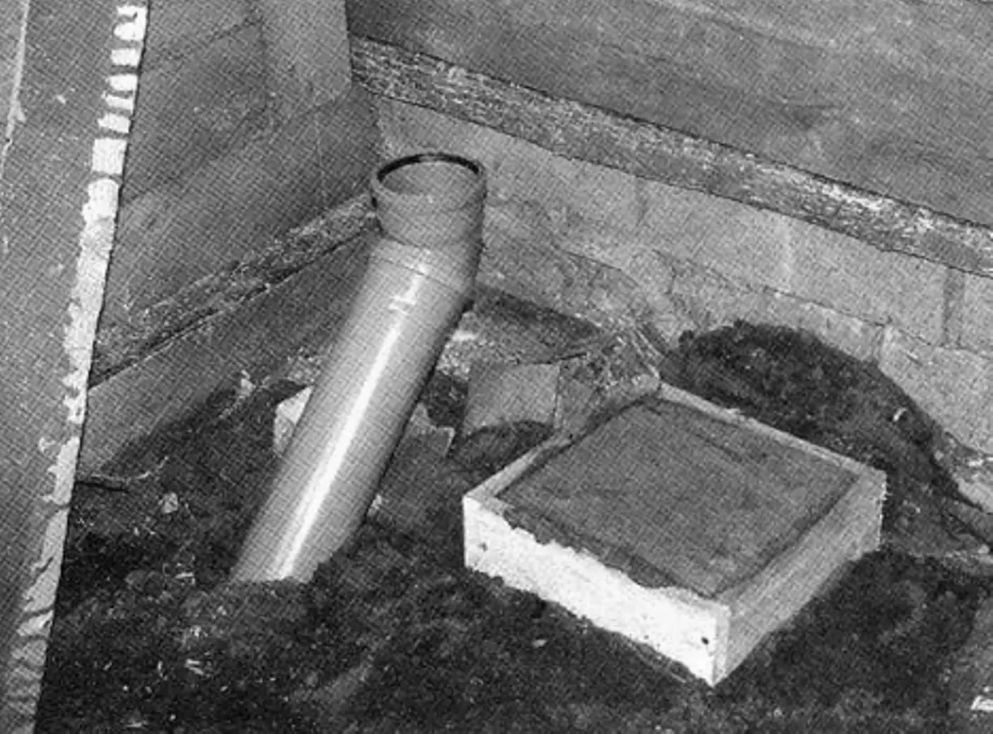 Toilet drain pipes. Nearby is a concrete post for the inner floor crossbeam in the bathroom