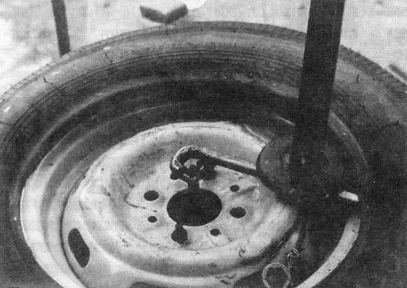 Tire demounting process using the fixture with the stock jack and lug wrench